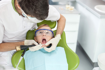Professional male dental doctor is treating his patient