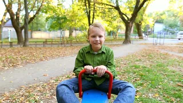 Cheerful funny kid playing at children playground on autumn day. Slow motion video footage
