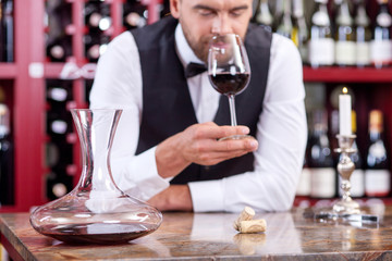 Handsome young male waiter is tasting red drink