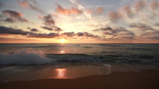 Sunset on the beach - Tranquil idyllic scene of a golden sunset over the sea, waves slowly splashing on the sand.
