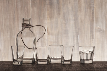 Empty bottle and shots on the wooden bar counter