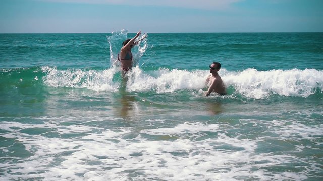 Happy Couple Having Fun on Ocean Waves, slow motion
