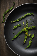Green peppercorns in old pan on rustic wood background, Dark moo