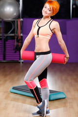 Fototapeta na wymiar Attractive fitness girl is posing with yoga mat