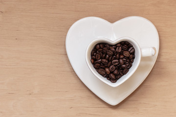 Heart shaped cup with coffee beans on wooden table