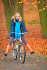 Happy active woman riding bike in autumn park.