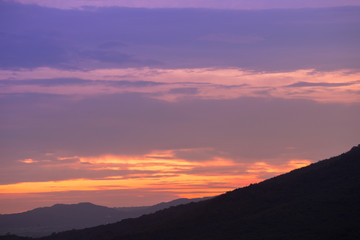 Silhouette of sunset over dark black mountain