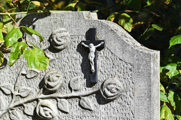 Cross and flower on the tombstone in the public cemetery