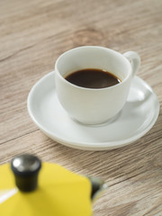  Cup of coffee and Yellow coffee maker kettle on wooden table