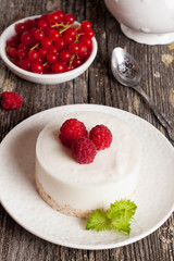 cheesecake with fresh raspberries and mint leaves on top on a wo