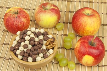 Chocolate cereal balls in a bowl of bamboo. Healthy breakfast with fruit and milk. A diet full of energy and fiber for athletes. Quick to prepare homemade breakfast.
