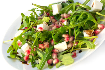 arugula salad with feta cheese and pomegranate on a white plate