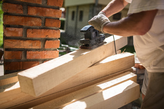 Senior Man Finishing Wooden Beam With Sander