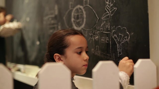 Ni&ntilde;a concentrada dibujando en la pizarra