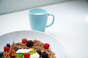 Close up muesli with berries dipped with yougurt in white dish an