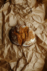 Whole grain round bread on creased crafted paper