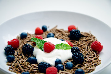 Close up muesli with berries and yougurt in white dish for breakf
