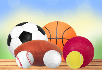 Sport balls on wooden table over nature background