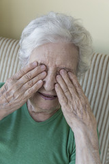 
senior woman closing her eyes with wrinkled hands