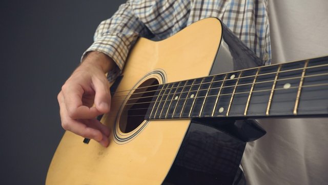 Strumming acoustic guitar, rock musician playing guitar, unplugged music performance