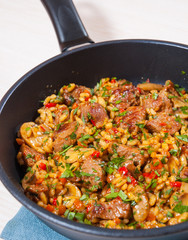 Rice with meat, vegetables and mushrooms in a frying pan