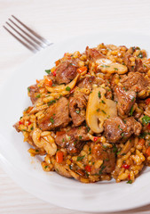 Rice with meat, vegetables and mushrooms on plate