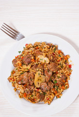 Rice with meat, vegetables and mushrooms on plate
