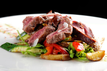 Grilled sliced roast beef on potato and salad