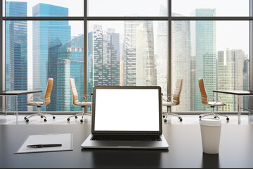 A workplace in a modern panoramic office in Singapore. A laptop with white screen, notepad and a coffee cup are on the black table. Open space. 3D rendering. Toned image.
