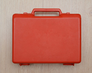 Red suitcase is on the wooden background
