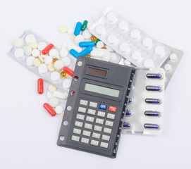 Tablets with capsules in blister packs and calculator lying on