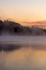 Fototapeta premium colorful fall sunrise by a lake with mist over the water