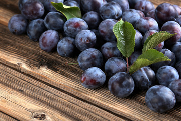 Fresh plums on the brown wooden background