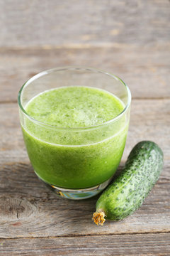Glass of fresh cucumber juice on grey wooden table