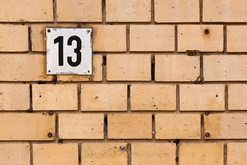Fototapeta na wymiar Hausnummer 13 auf einer Wand aus alten orangen Ziegelsteinen