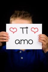 Child holding sign with Italian words Ti Amo - I Love You