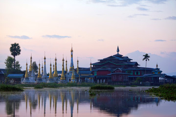 Naklejka premium Ancient stupa and wooden monastery at sunrise on Inle lake, Myanmar