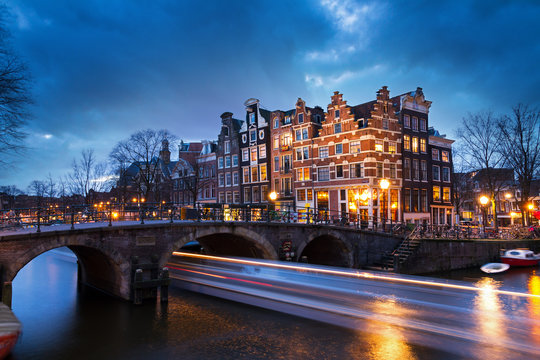 Beautiful view on the Brouwersgracht in Amsterdam, the Netherlands, with a passing canal tour boat after sunset