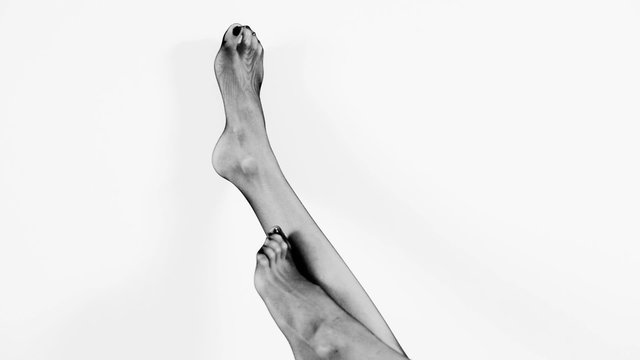 sexy female feet in black stockings at white background