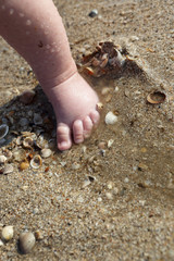 Newborn baby boy foot in the sand