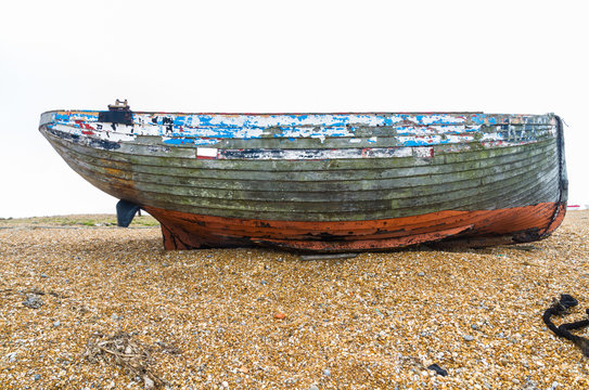 Old derelict boat on pebble beach.