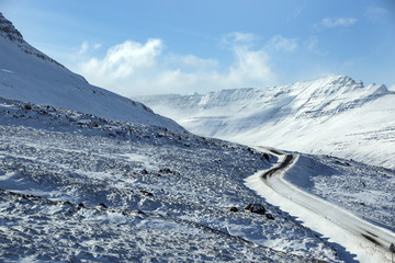 Obraz premium Snowy and icy road with volcanic mountains in wintertime