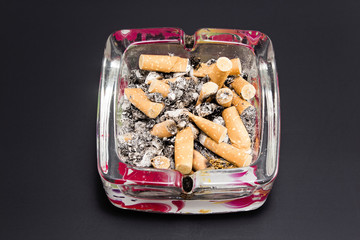 Ashtray with cigarette butts on a black background