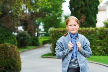 Outdoor portrait of a cute little girl wearing grey coat