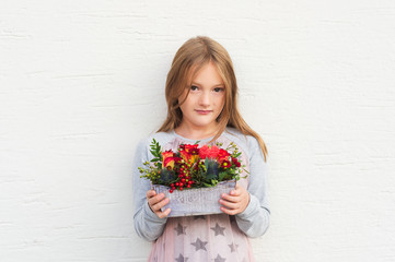 Portrait of a cute little girl holding autumn decoration with flowers