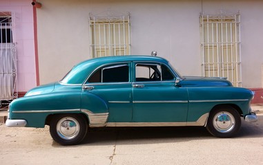 Classic American car as taxi parked in the street in front of old buildings in historic Trinidad, Cuba. 