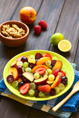 Fresh fruit salad of grape, strawberry, plum and nectarine served on plate, photographed on dark wood with natural light (Selective Focus, Focus in middle of salad)