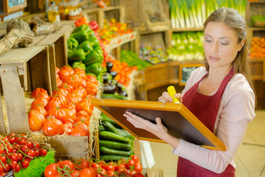 Woman writing sign for fruit and veg