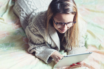 woman lying in bed with digital tablet touching with finger in m