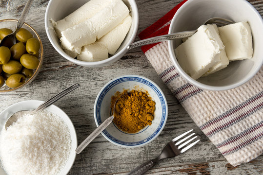 Formaggi cremosi, olive verdi denocciolate e curry in piccoli contenitori su un tavolo